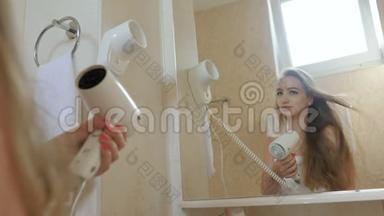 穿着浴巾的漂亮少女正在浴室里用吹风机照镜子